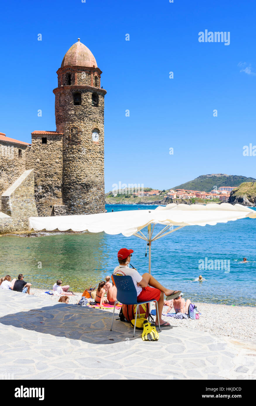 Bagnino di spiaggia ombreggiata da un ombrellone sulla Plage Boramar vicino alla torre di Notre Dame des Anges, Collioure, Côte Vermeille, Francia Foto Stock