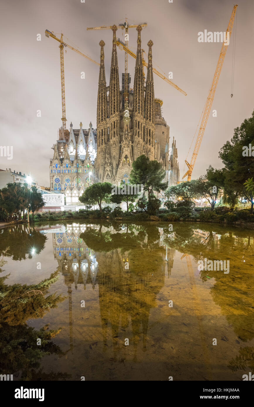 La Sagrada Familia illuminata di notte, riflettendo nell'acqua. La cattedrale fu progettata da Antoni Gaudi e è stato in costruzione dal 188 Foto Stock