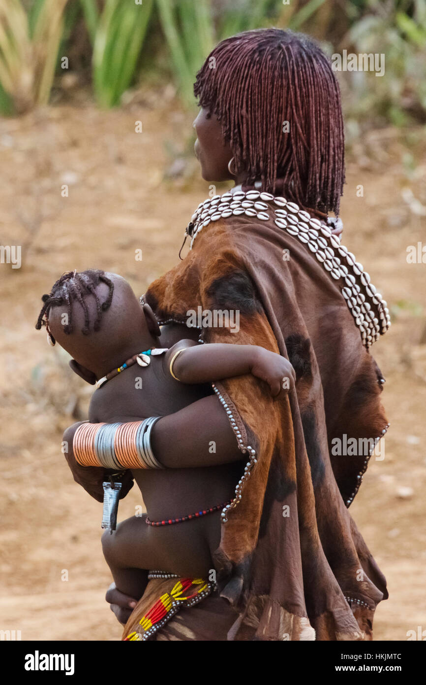 Hamar tribù donna bambino portando in Hamar Village, Sud Omo, Etiopia Foto Stock