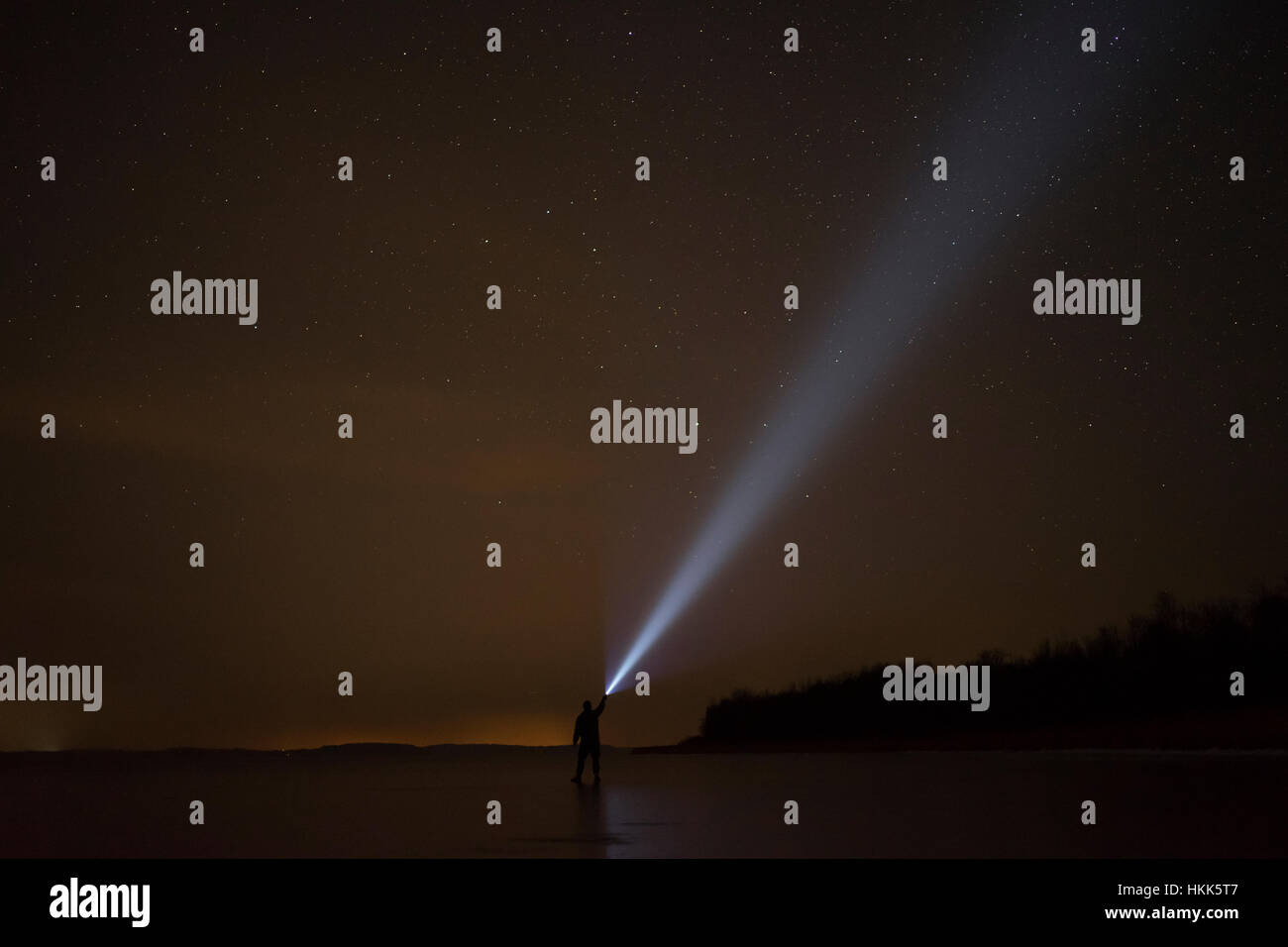Uomo di notte splende con la torcia elettrica. In piedi sul lago ghiacciato. Foto Stock
