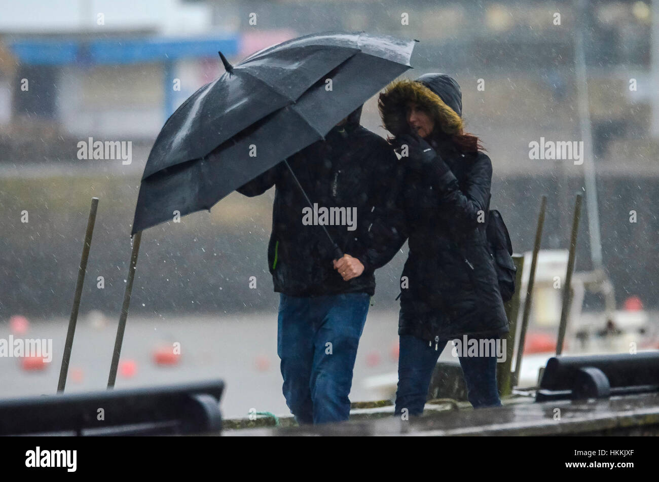 West Bay, Dorset, Regno Unito. Il 29 gennaio 2017. Regno Unito Meteo. Un giovane alle prese con un ombrello al vento forte come heavy rain falls a West Bay nel Dorset. Credito Foto: Graham Hunt/Alamy Live News. Foto Stock