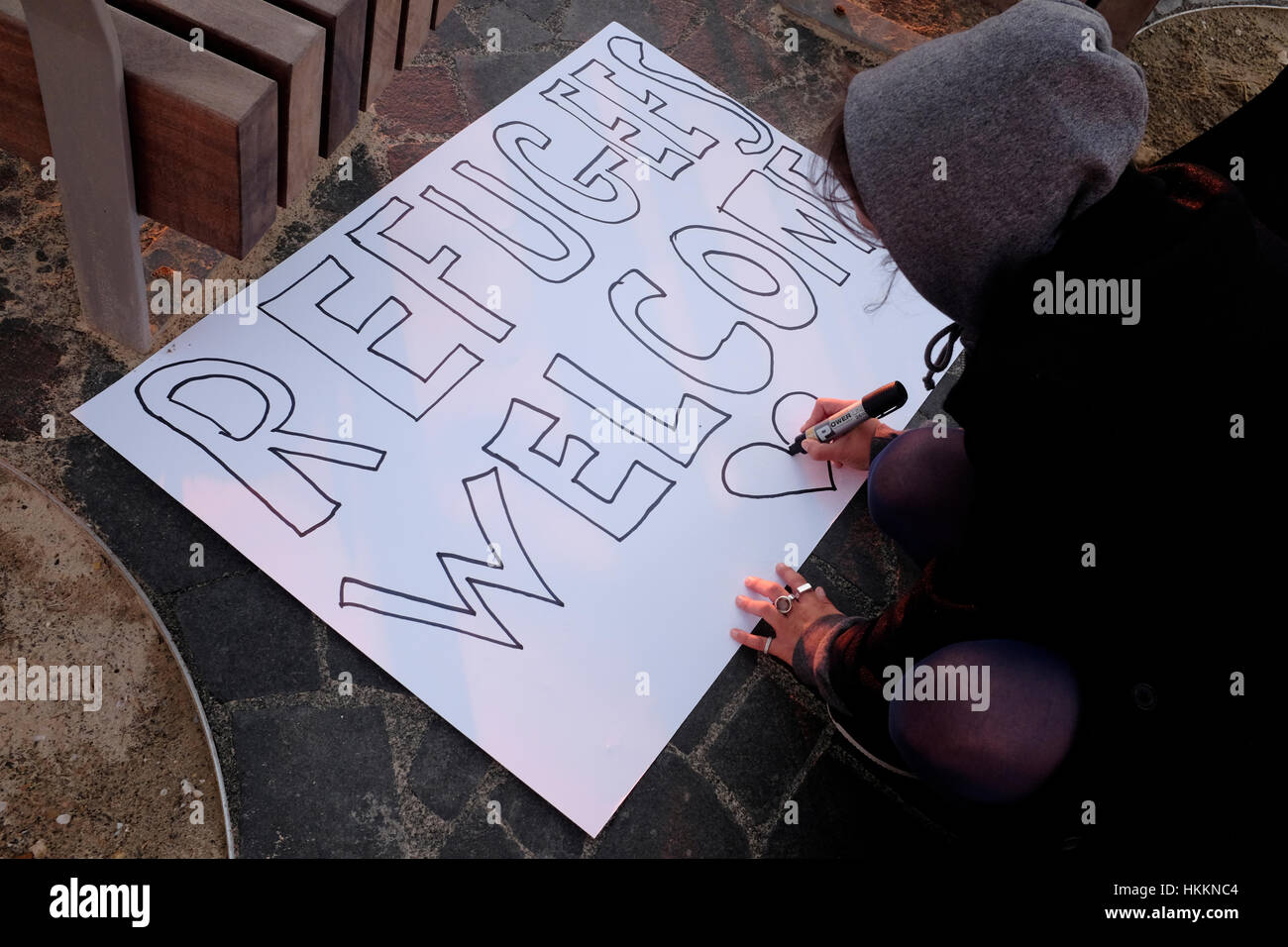Un israeliano prepara un cartello in inglese che recita "i rifugiati sono benvenuti" durante una manifestazione contro le politiche del presidente Donald Trump‘s nei confronti dei musulmani e dei rifugiati al di fuori dell'ambasciata americana a Tel Aviv, Israele. Foto Stock
