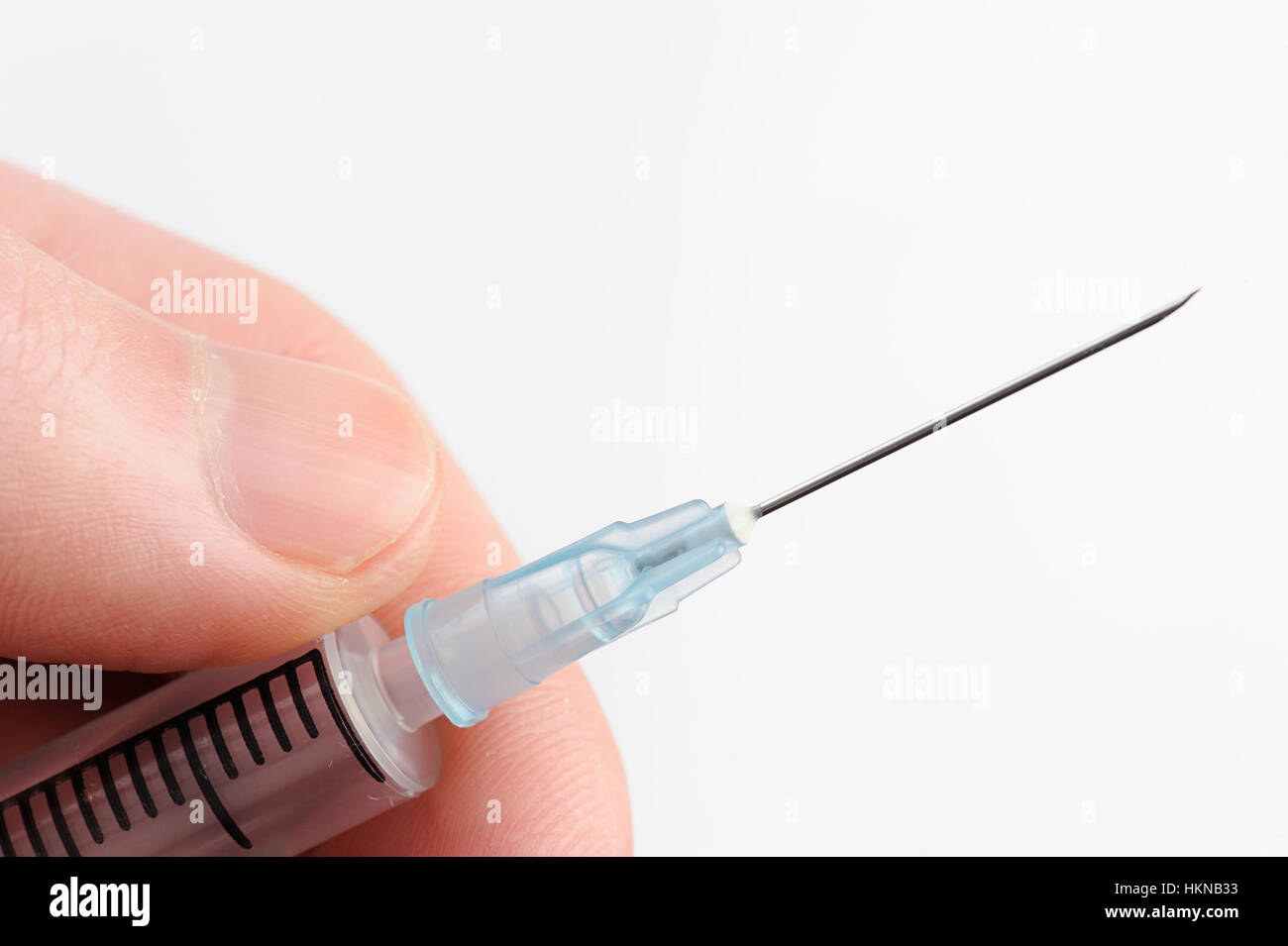 Macro di siringa con ago in mano su bianco Foto Stock