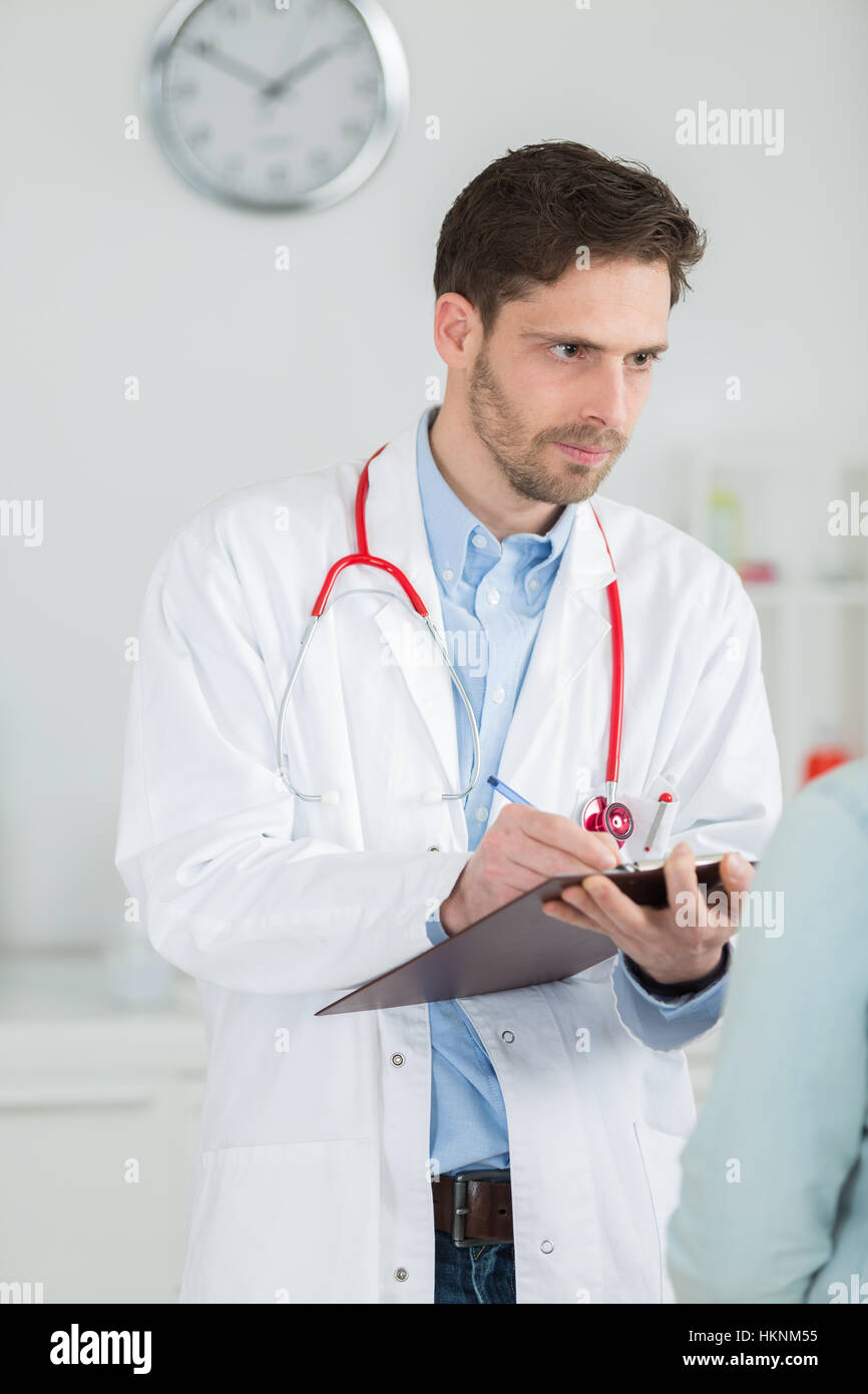 Un giovane maschio medico a scrivere note Foto Stock