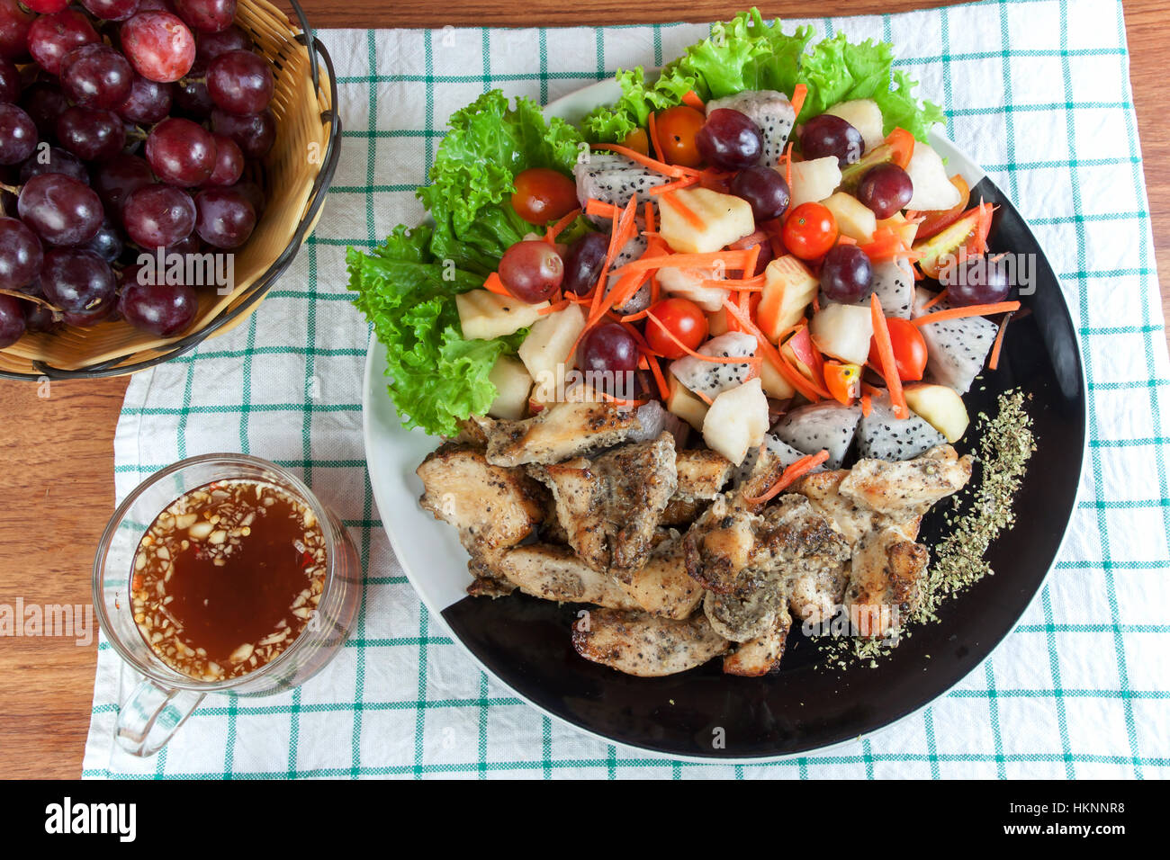 Cibo sano. Pollo grigliato cosparso con origano e frutta mix insalata piccante su una piastra. Foto Stock