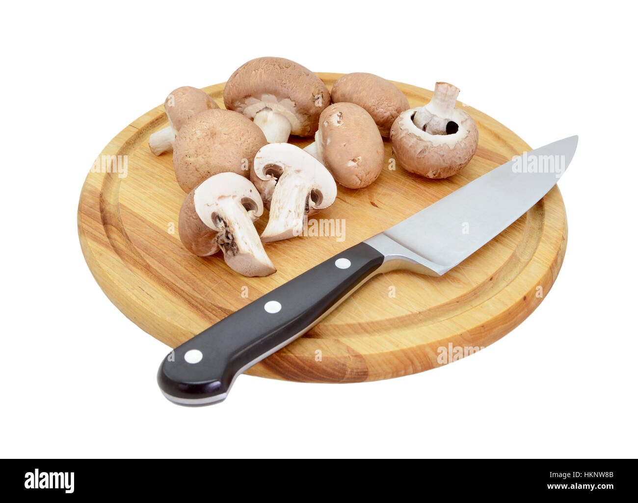 Intero e dimezzato i funghi castagne su un tagliere di legno con la lama di un coltello, isolato su sfondo bianco Foto Stock