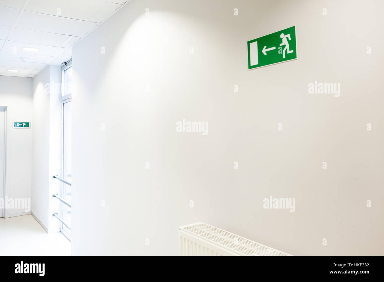 In corridoio c'è un radiatore con un segnale di uscita di emergenza Foto Stock