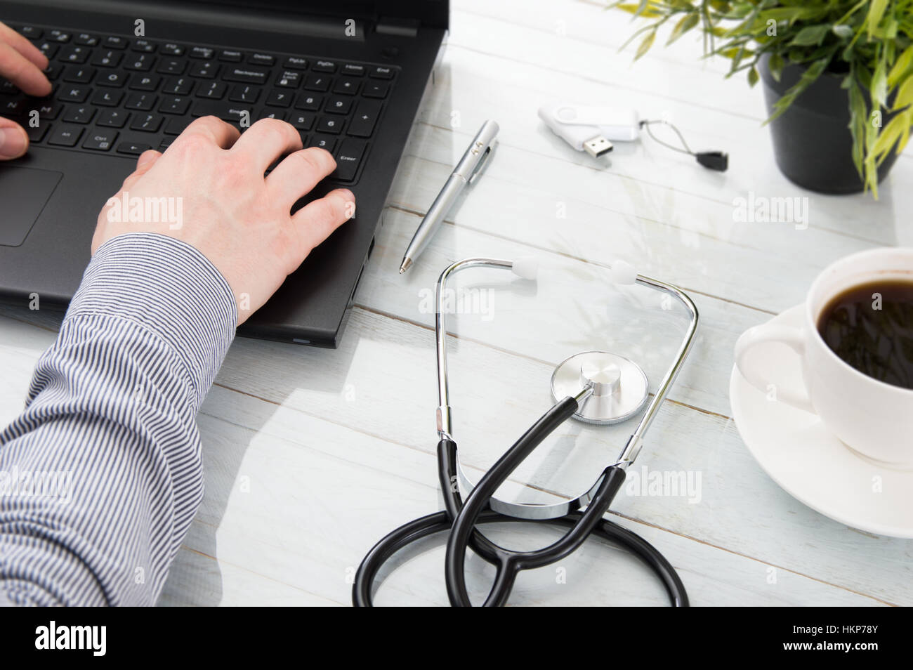 Dottore le mani sul computer portatile e uno stetoscopio sulla scrivania. Foto Stock