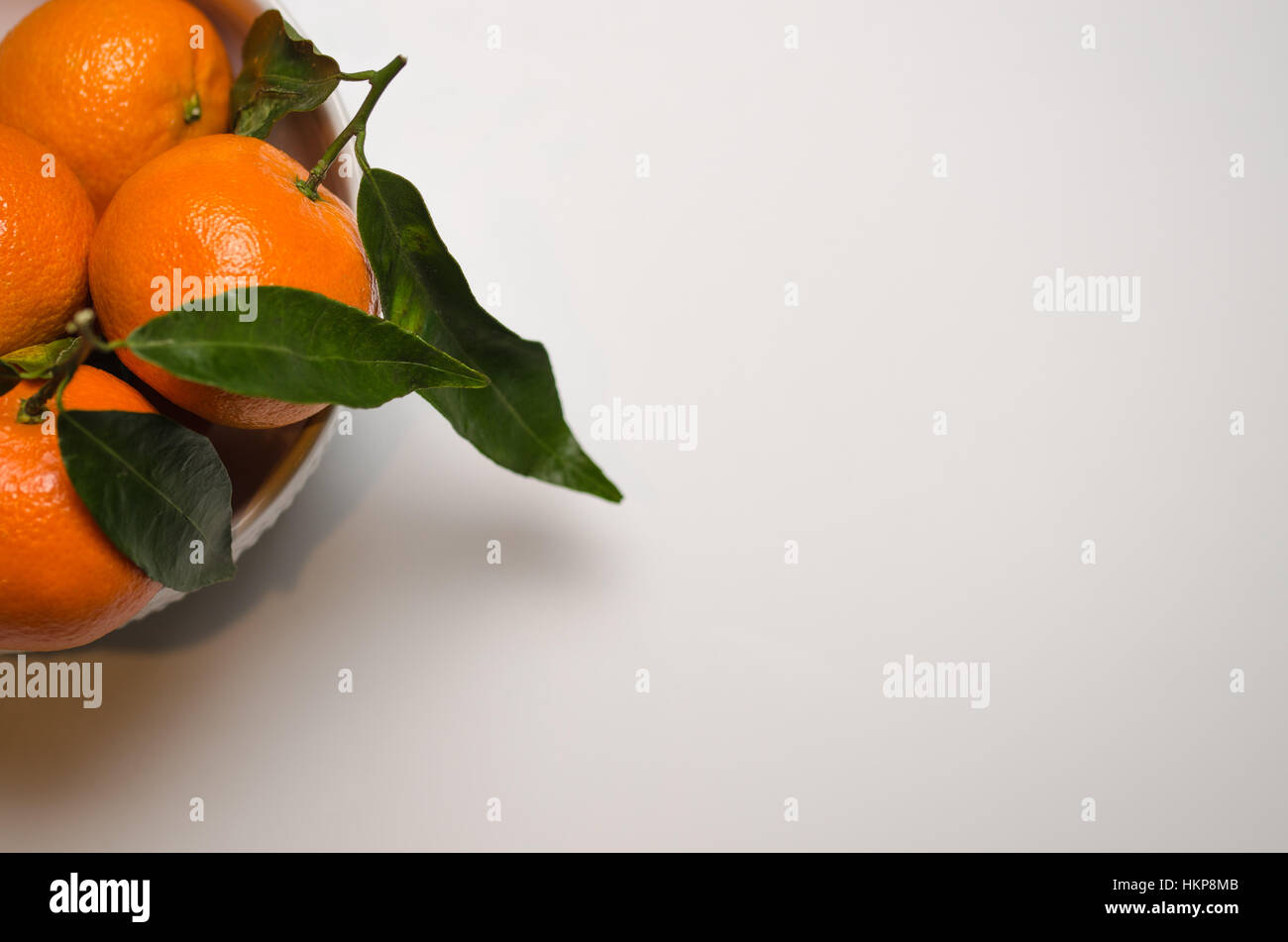 Una ciotola di Clementina fresca frutta tropicale su sfondo bianco con spazio per il testo. Foto Stock