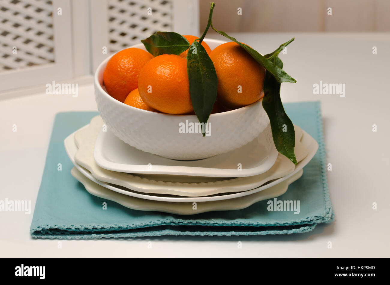 Una bella tazza di Clementina su una pila di piastre su sfondo bianco. Foto Stock