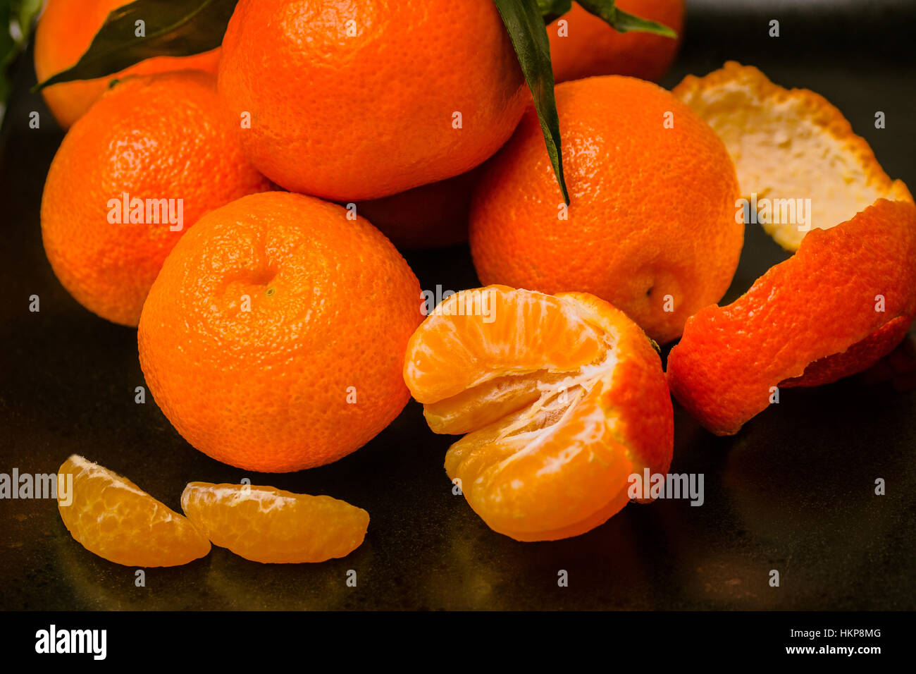 Più fresche Clementine succosa frutta tropicali sulla piastra nera. Foto Stock