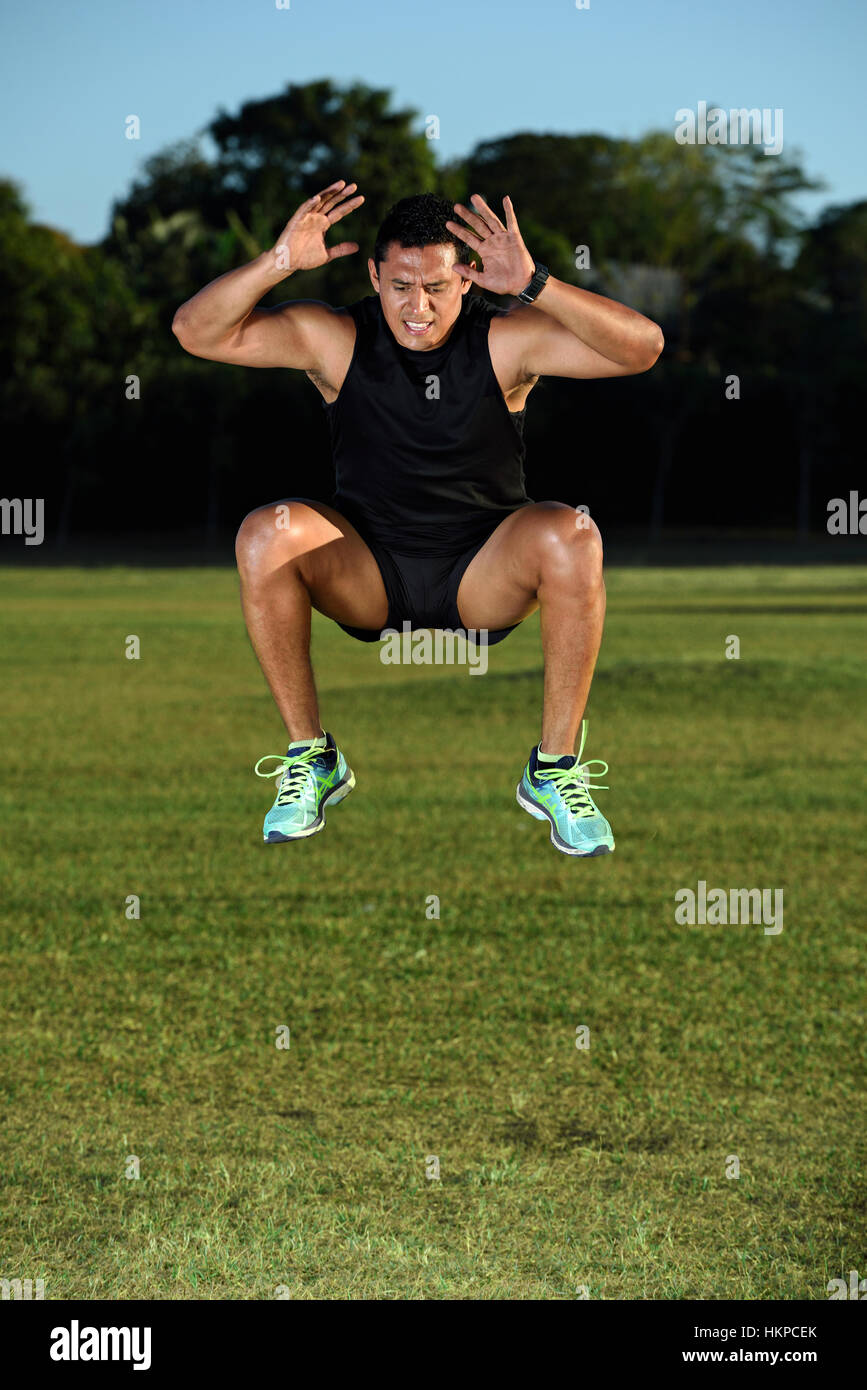 Uomo sportivo jumping alta sul prato verde erba park Foto Stock