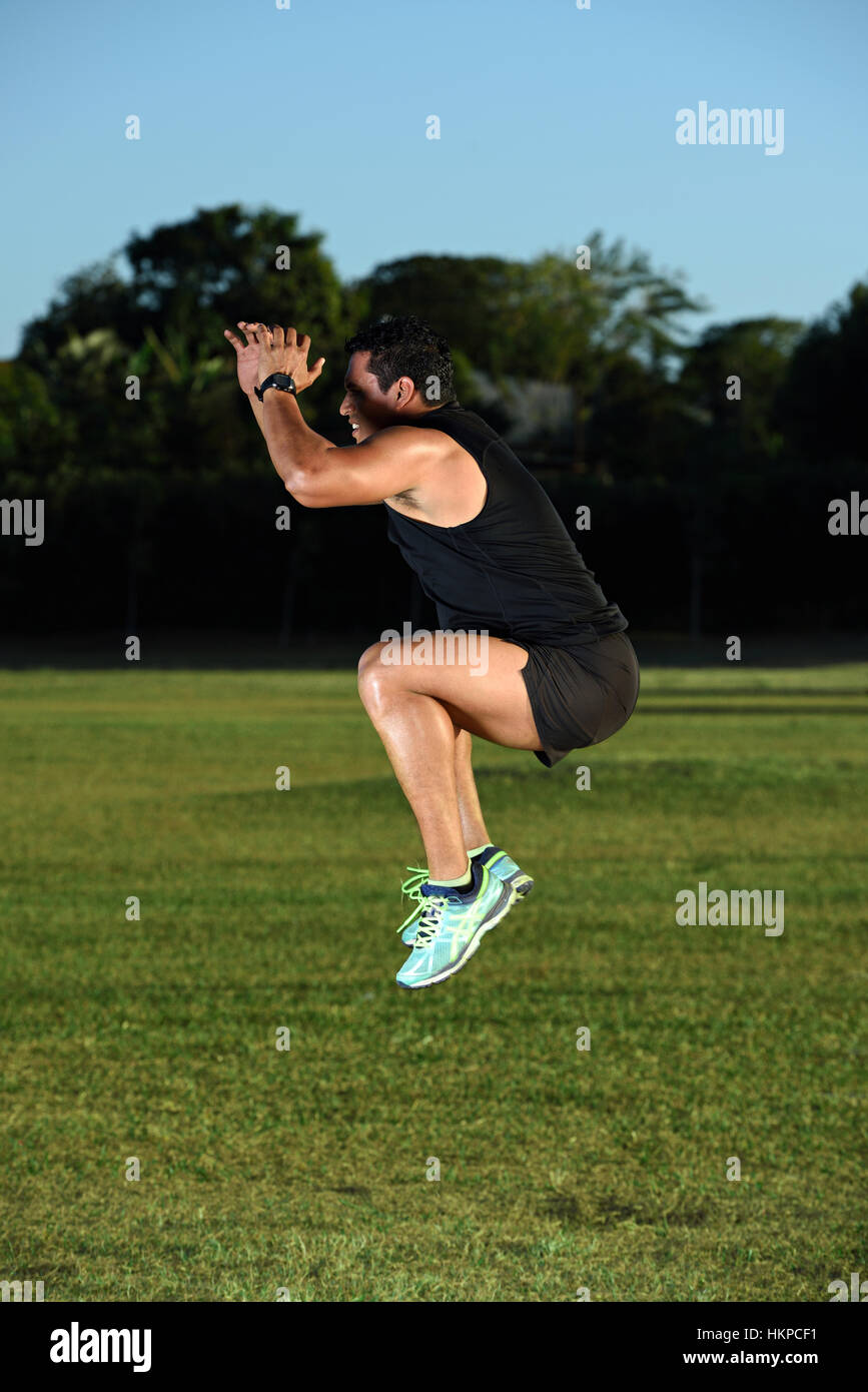 Uomo sportivo di saltare sul parco verde erba Foto Stock
