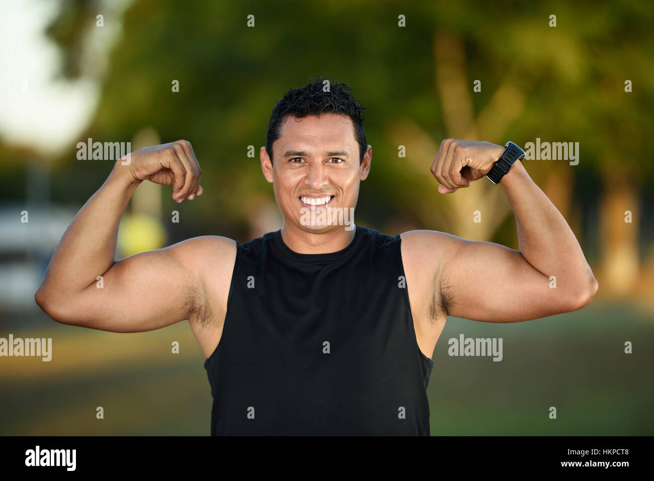 Sport uomo ispanico che mostra i muscoli su green park Foto Stock