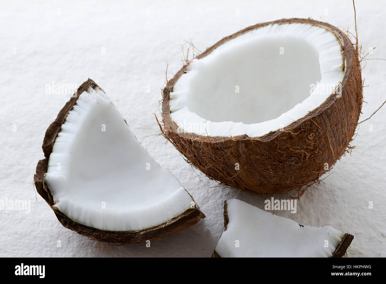 In prossimità di tutta una noce di cocco crepe aperte su uno sfondo bianco. Foto Stock