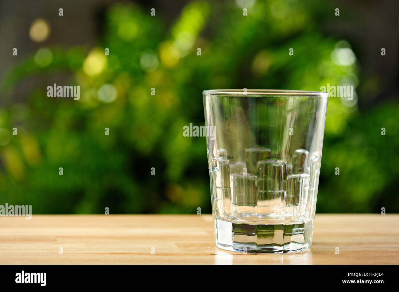 Bicchiere vuoto sul tavolo con giardino verde sullo sfondo Foto Stock