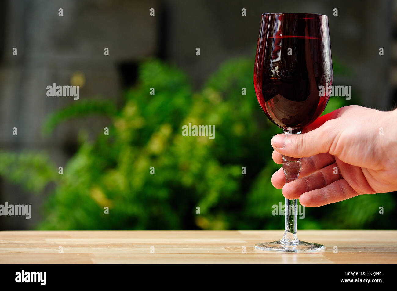 Vetro rosso con drink in mano sul parco verde di sfondo Foto Stock