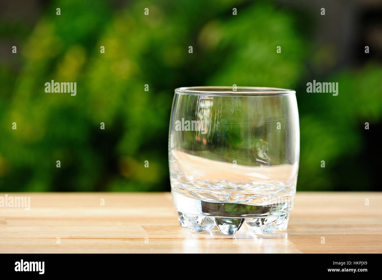 Vuoto in vetro di whisky sul tavolo verde sullo sfondo del parco Foto Stock