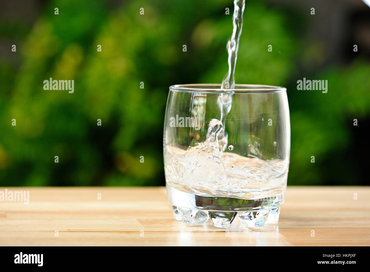Versare acqua nella vuota di whisky in vetro verde del giardino Foto Stock