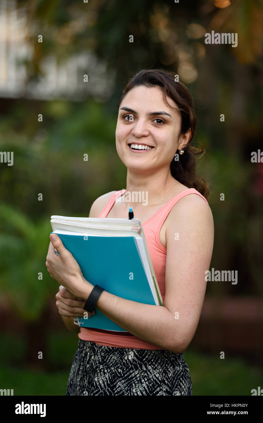 Studente sorridente ragazza latino con libri in posizione di parcheggio Foto Stock