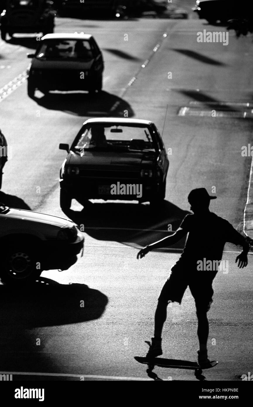 Stagliano giovinezza su skateboard lungo "l' Ave nel quartiere universitario attraversando via del tramonto, Seattle nello Stato di Washington STATI UNITI D'AMERICA Foto Stock