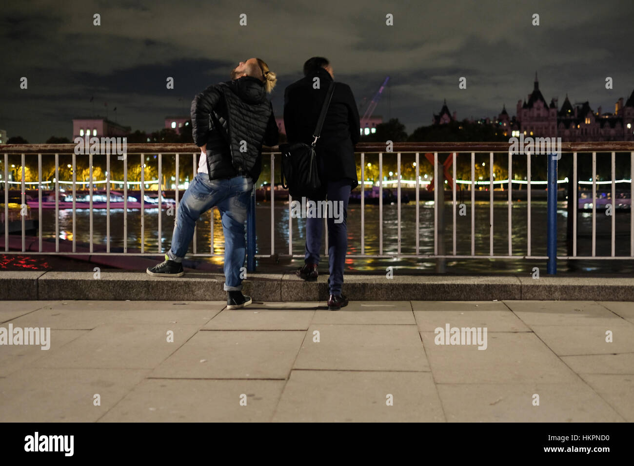 Due giovani uomini godendo di viste del Bankside di notte Foto Stock