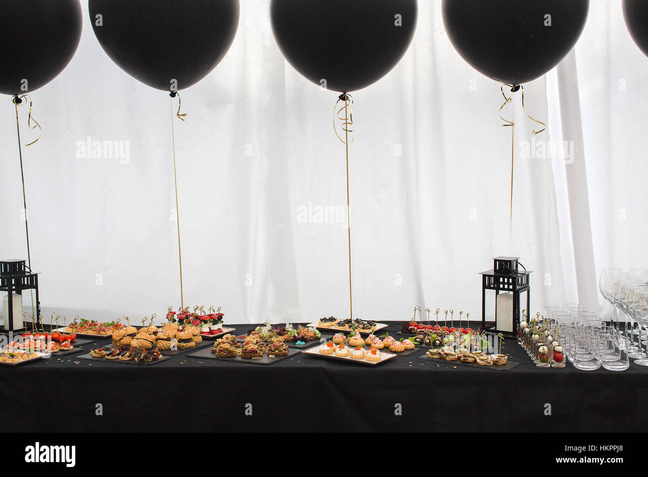 Diversi snack sulla tavola nera e palloncini Foto Stock