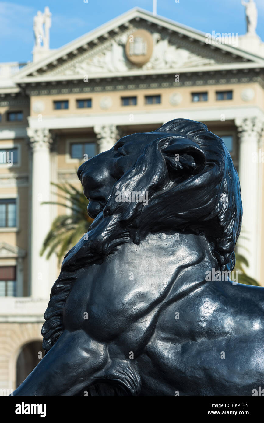 Uno dei Lions a La Porta de la Pau square, con Gobierno Militar edificio per la parte posteriore. Barcellona, Spagna. Foto Stock