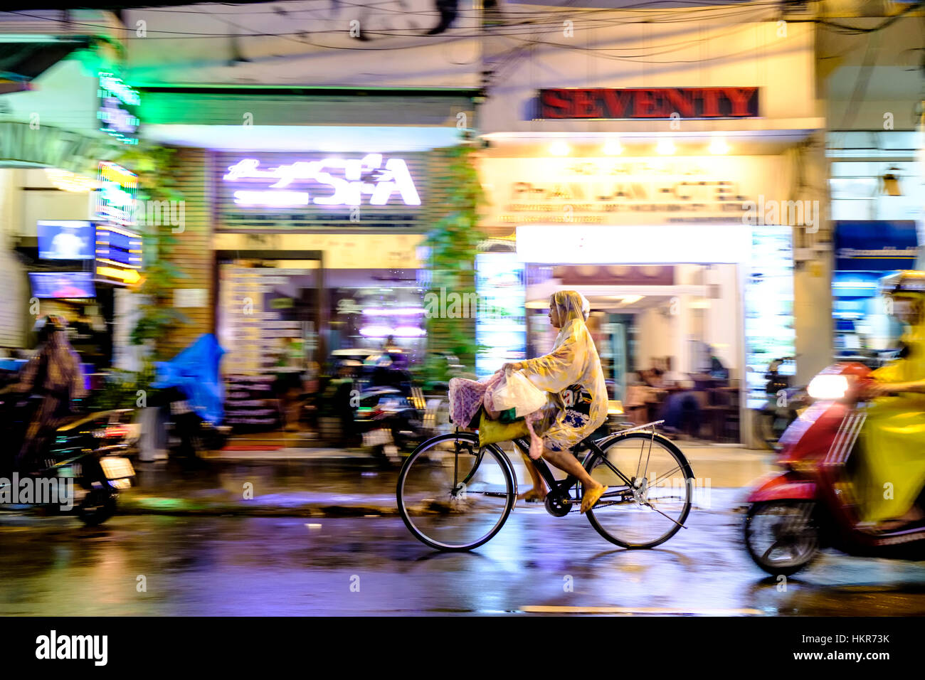 Ciclista in una strada piovosa, ho Chi Minh città (Saigon), Vietnam, Sud-est asiatico Foto Stock