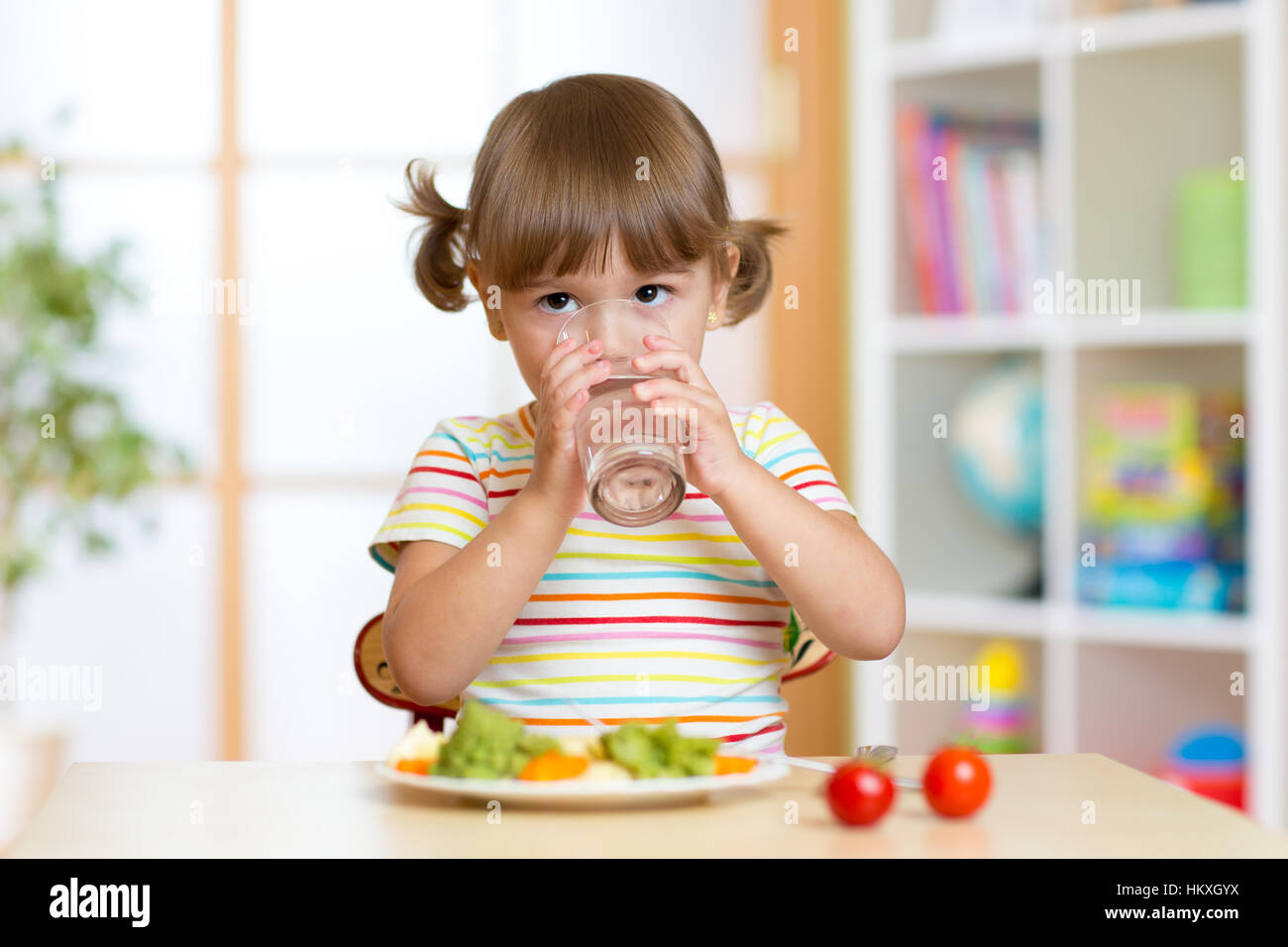 Bambino ragazza di mangiare e di bere in kindergarten Foto Stock