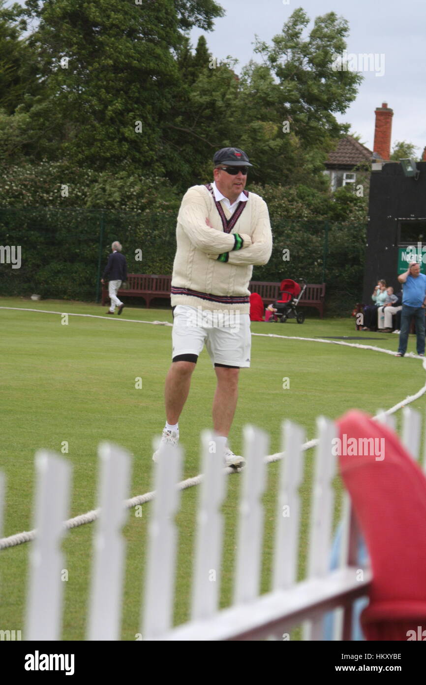 Battitore, giocatore di cricket in piedi con le braccia piegate vicino a white Picket Fence che indossa il cricket bianchi Foto Stock