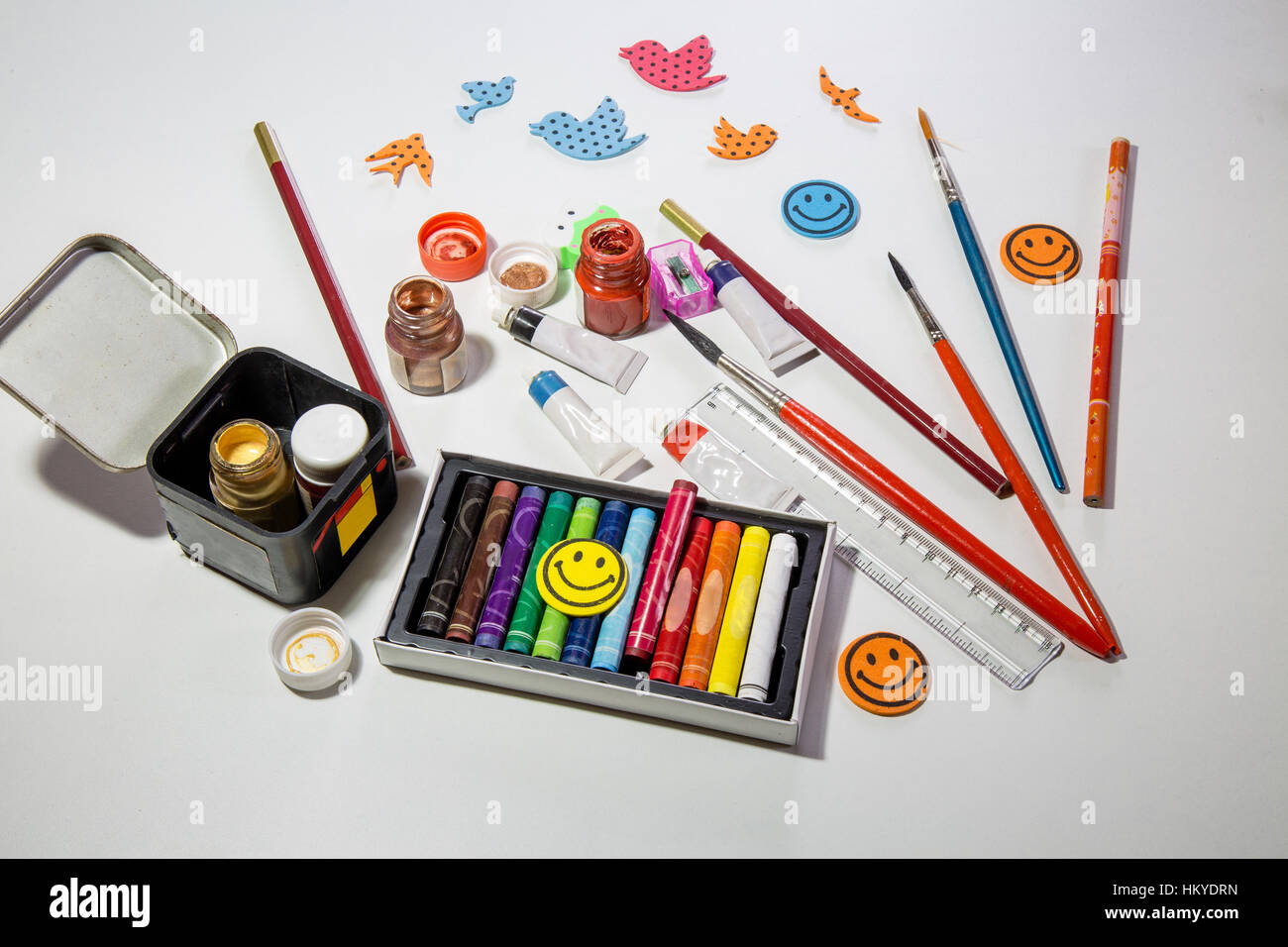 I bambini gli strumenti e gli articoli per la pittura e le opere creative con vernici di colore spazzole plastilina pastelli e matite sul tavolo bianco top Foto Stock