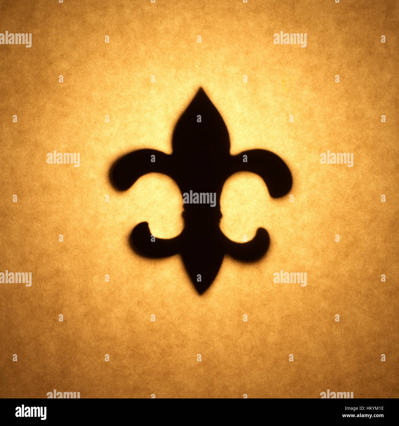 Silhouette retroilluminato di Fleur de Lis forma tagliata fuori contro il tono bruno carta, con spot evidenziare. Foto Stock