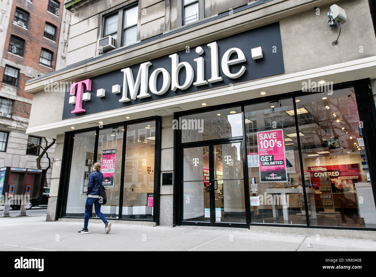 Una donna sta camminando da un T Mobile store in Manhattan. Foto Stock