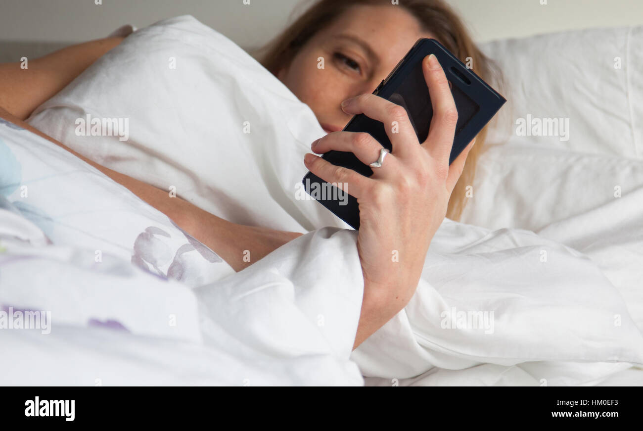 La donna a letto con smarthphone Foto Stock