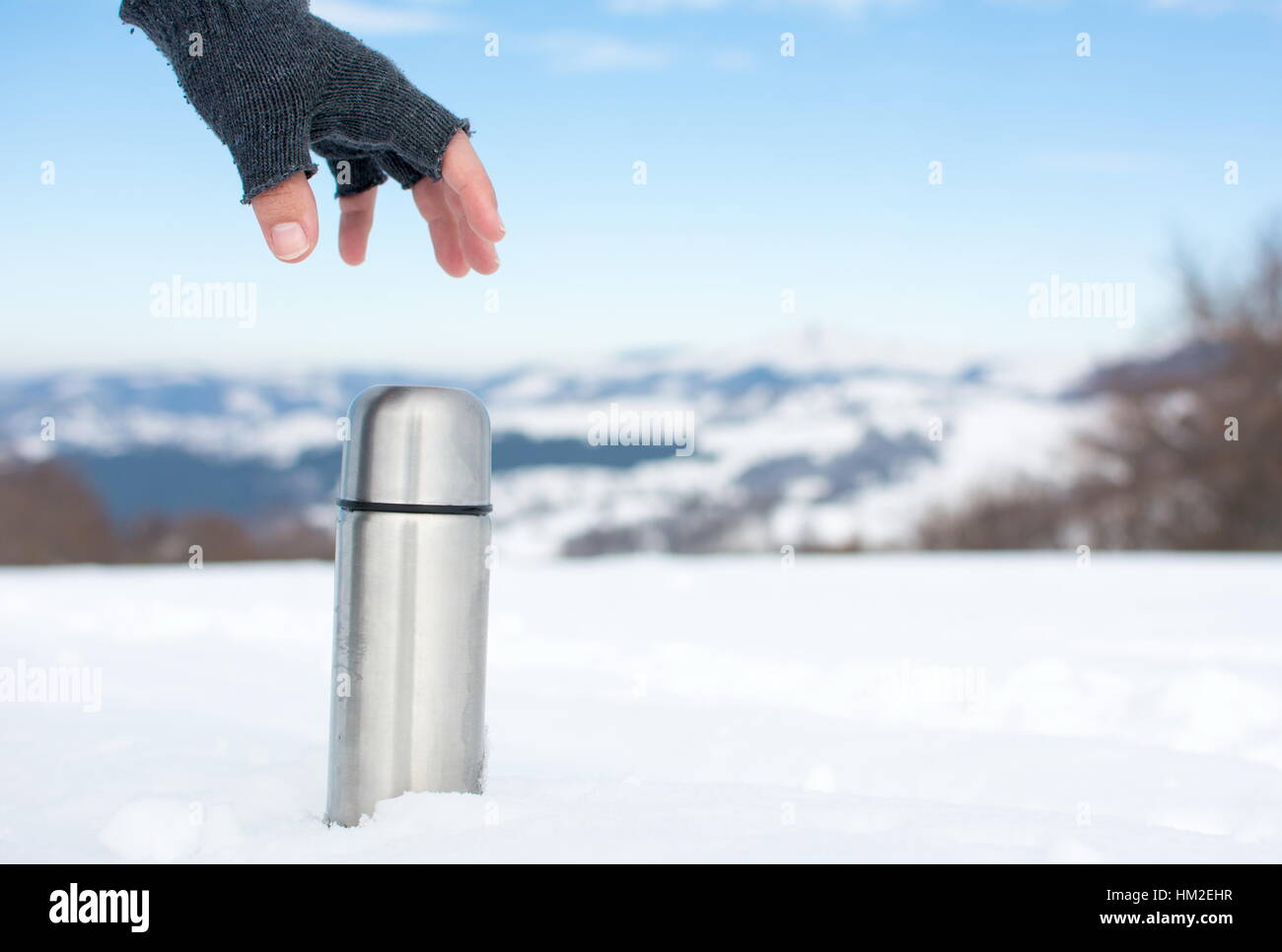 Uomo con un thermos in su una montagna innevata Foto Stock