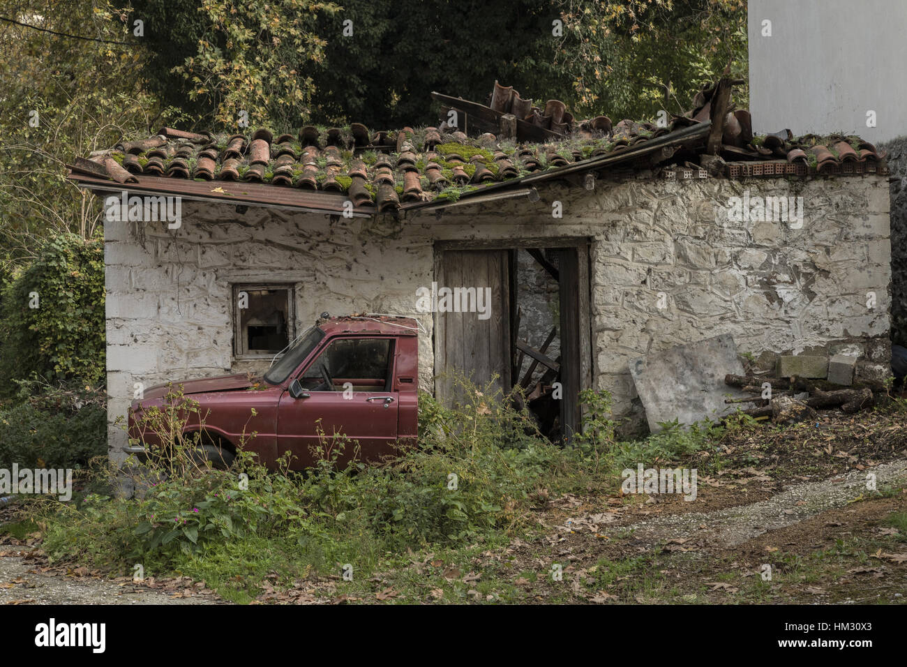 Cottage abbandonati con la metà di un auto al di fuori; Meteora, Grecia Foto Stock