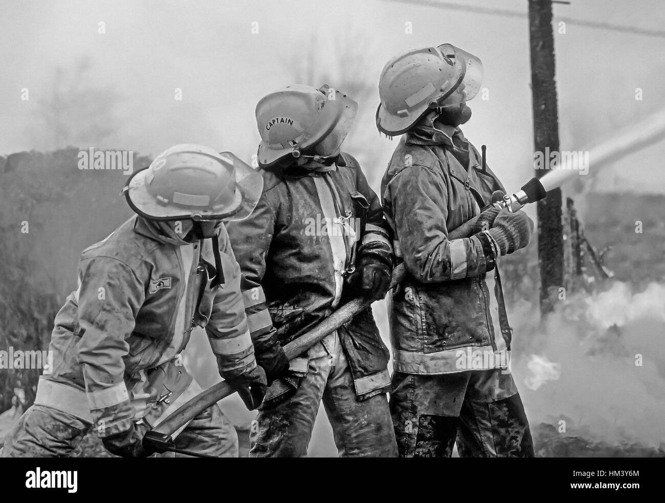 Tre vigili del fuoco battaglia un tripudio. Foto Stock
