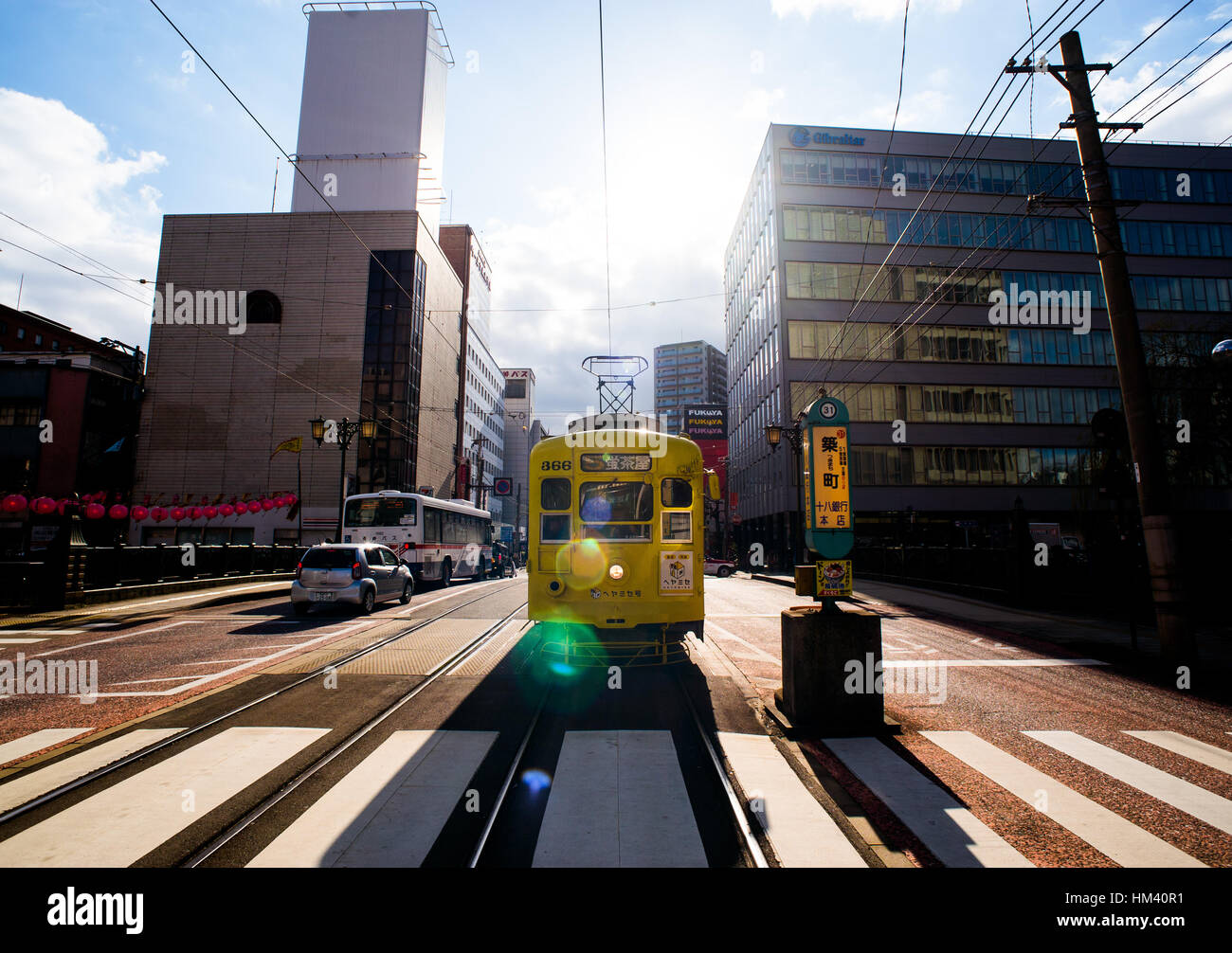 Vista frontale di un giallo vintage tram in attesa alle strisce pedonali a Nagasaki, in Giappone Foto Stock