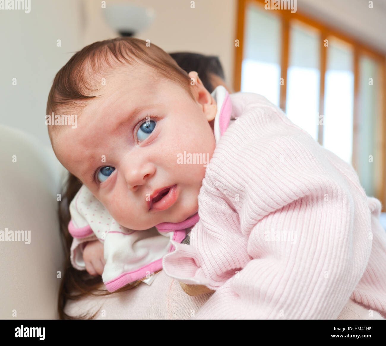 Ritratto di un simpatico neonato ragazza sulla sua madre lo spallamento a casa Foto Stock