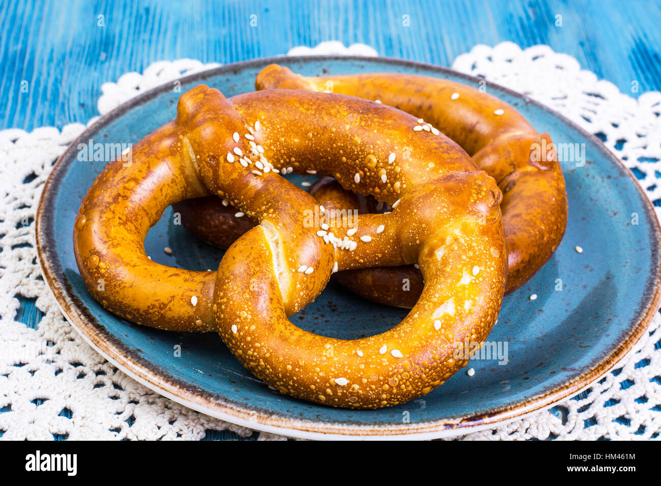 Pane appena sfornato pretzel con sale e formaggio su uno sfondo blu Foto Stock