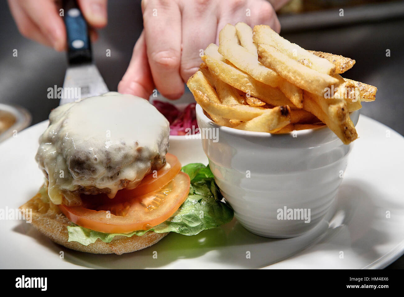 Cheeseburger e trucioli essendo servita su una piastra. Foto Stock