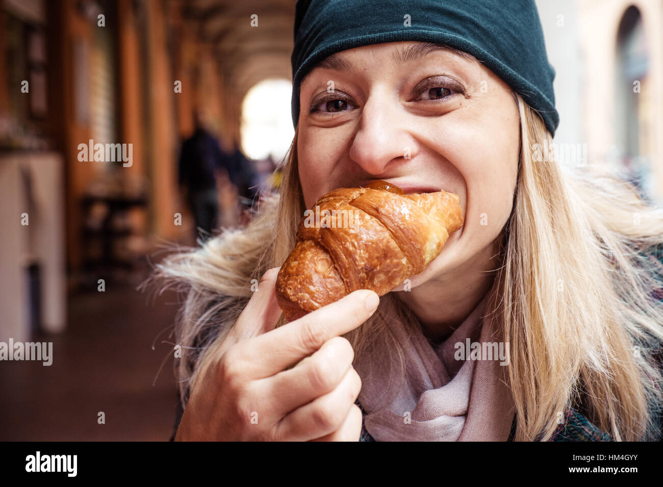 Donna bite croissant outdoor bar prima colazione Foto Stock