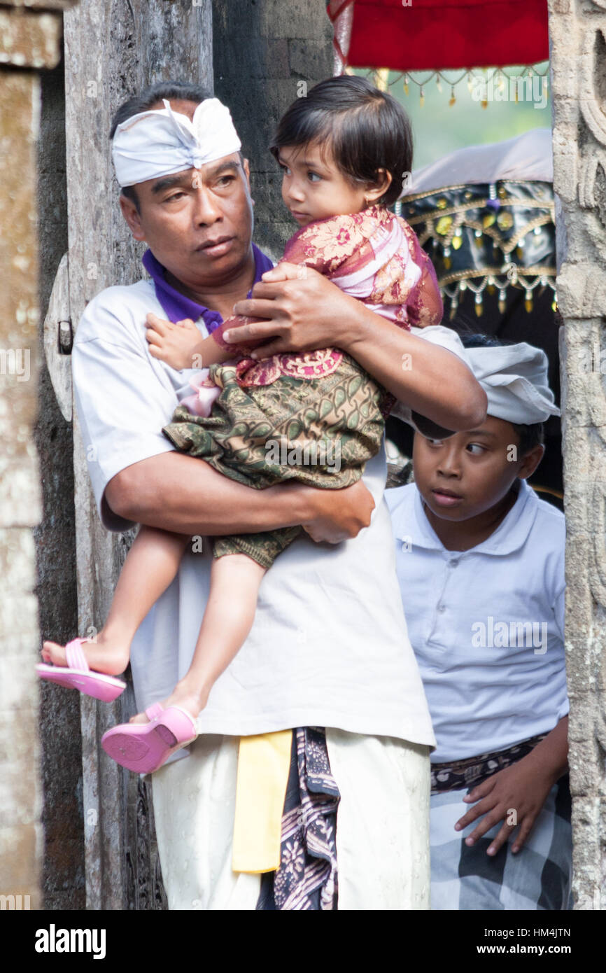 Uomo che porta il bambino attraverso la porta del tempio di Bali, Indonesia Foto Stock