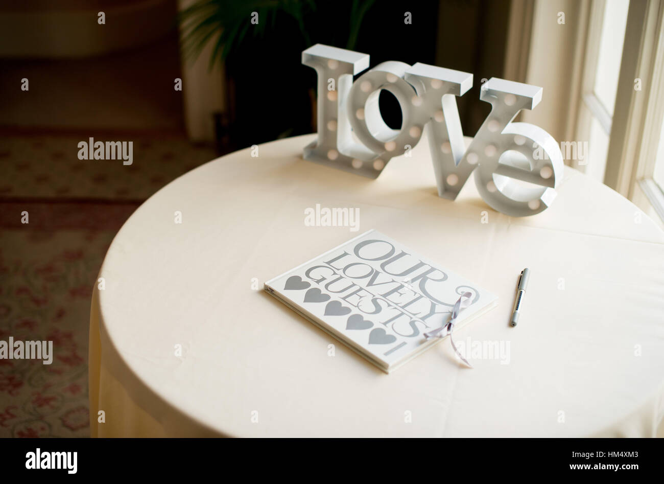 Wedding guestbook seduto su una tabella con una grande parola amore a un matrimonio in Sussex, Regno Unito. Gli ospiti firmare con i loro messaggi di cuore Foto Stock