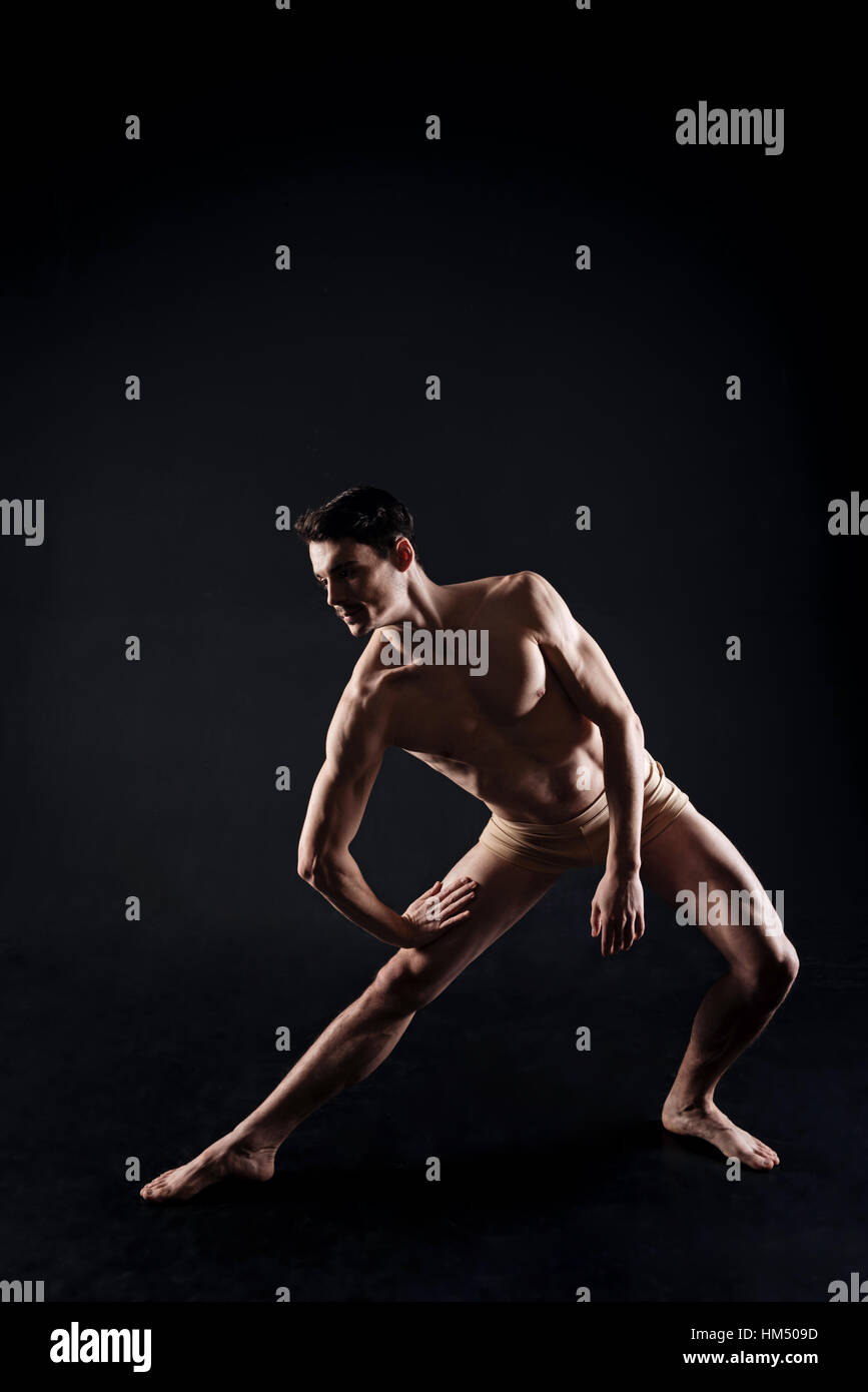 Coinvolti giovane atleta stretching nel colorato di nero studio Foto Stock