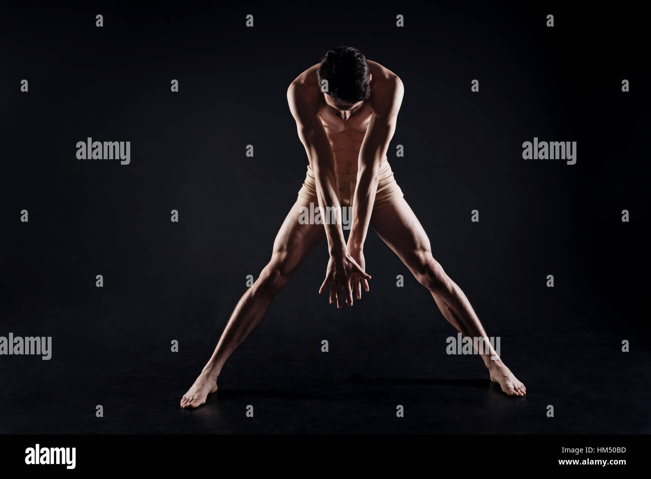 Slim concentrato stretching atleta in studio Foto Stock