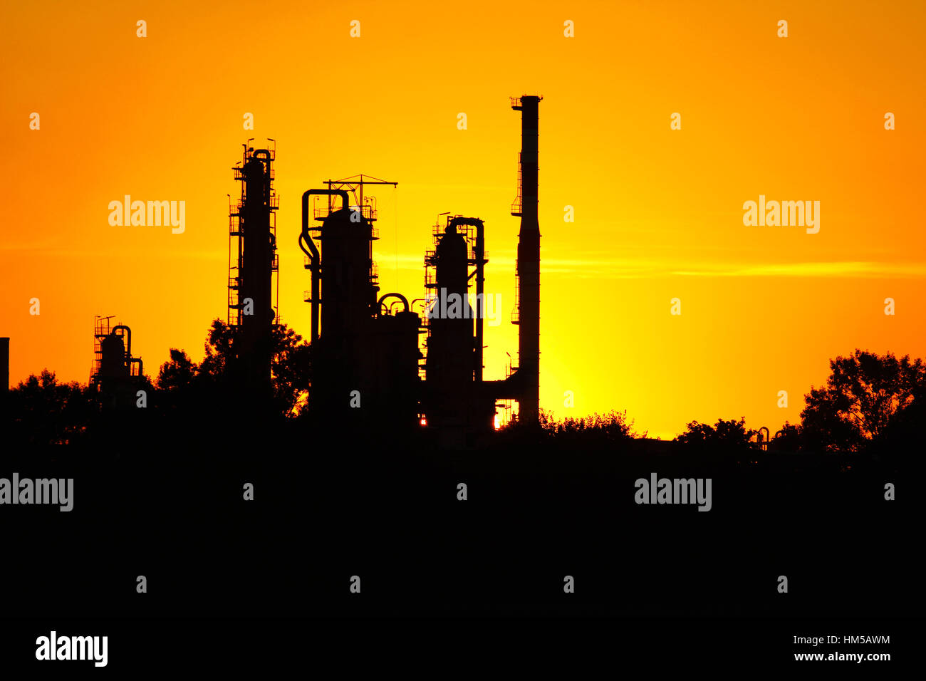 Silhouette di raffineria di greggio fabbrica durante il tramonto contro sun Foto Stock