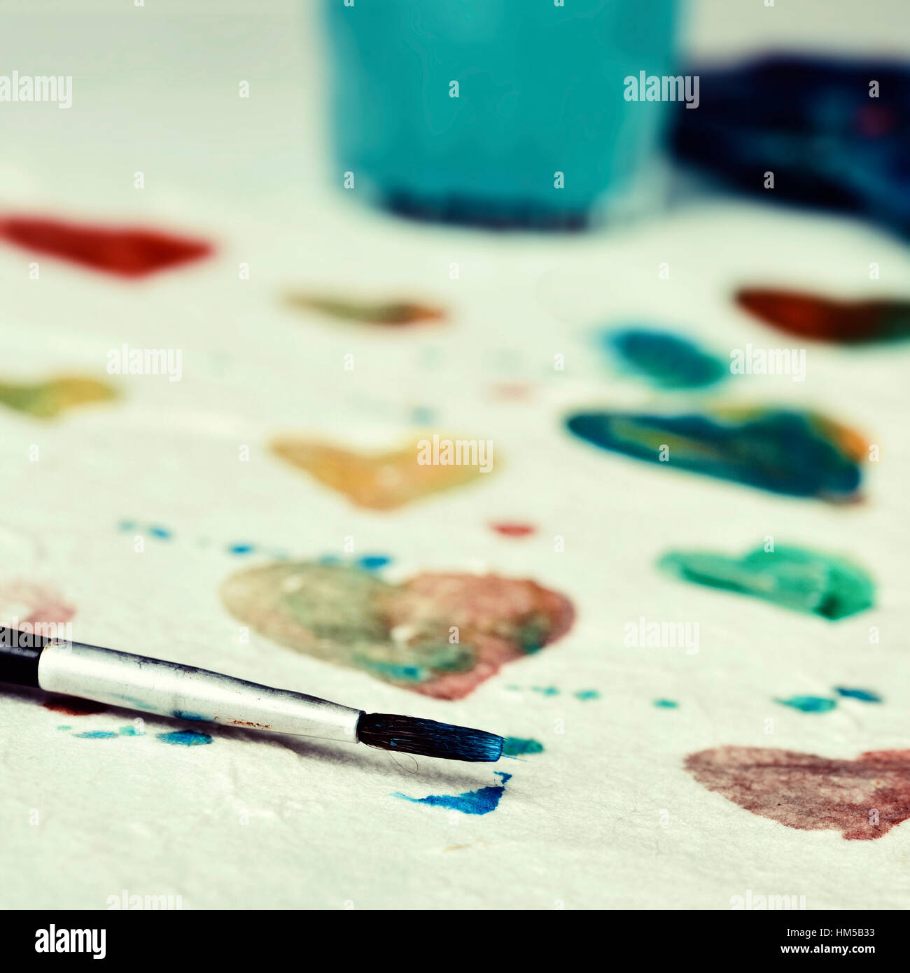 Primo piano di un pezzo di carta con alcuni cuori di colori diversi dipinti con vernice ad acquerello Foto Stock