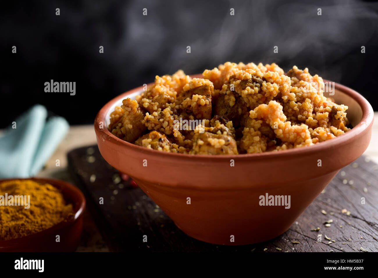 Primo piano di una casseruola di terracotta con il couscous con il pollo e le verdure su una tavola in legno rustico Foto Stock